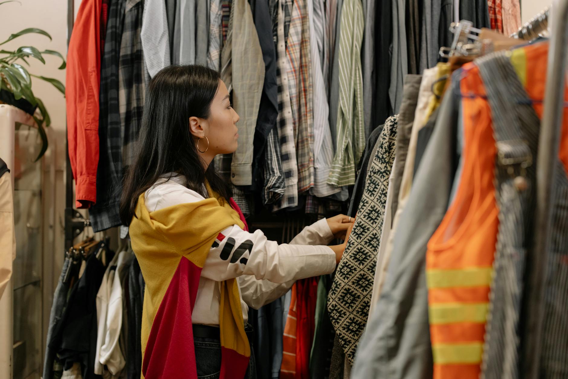 A young woman browsing clothes in a vintage store with colorful outfits. [pexels]