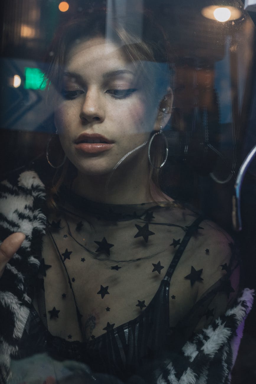 Artistic portrait of a woman in star-themed attire shot through glass. [pexels]