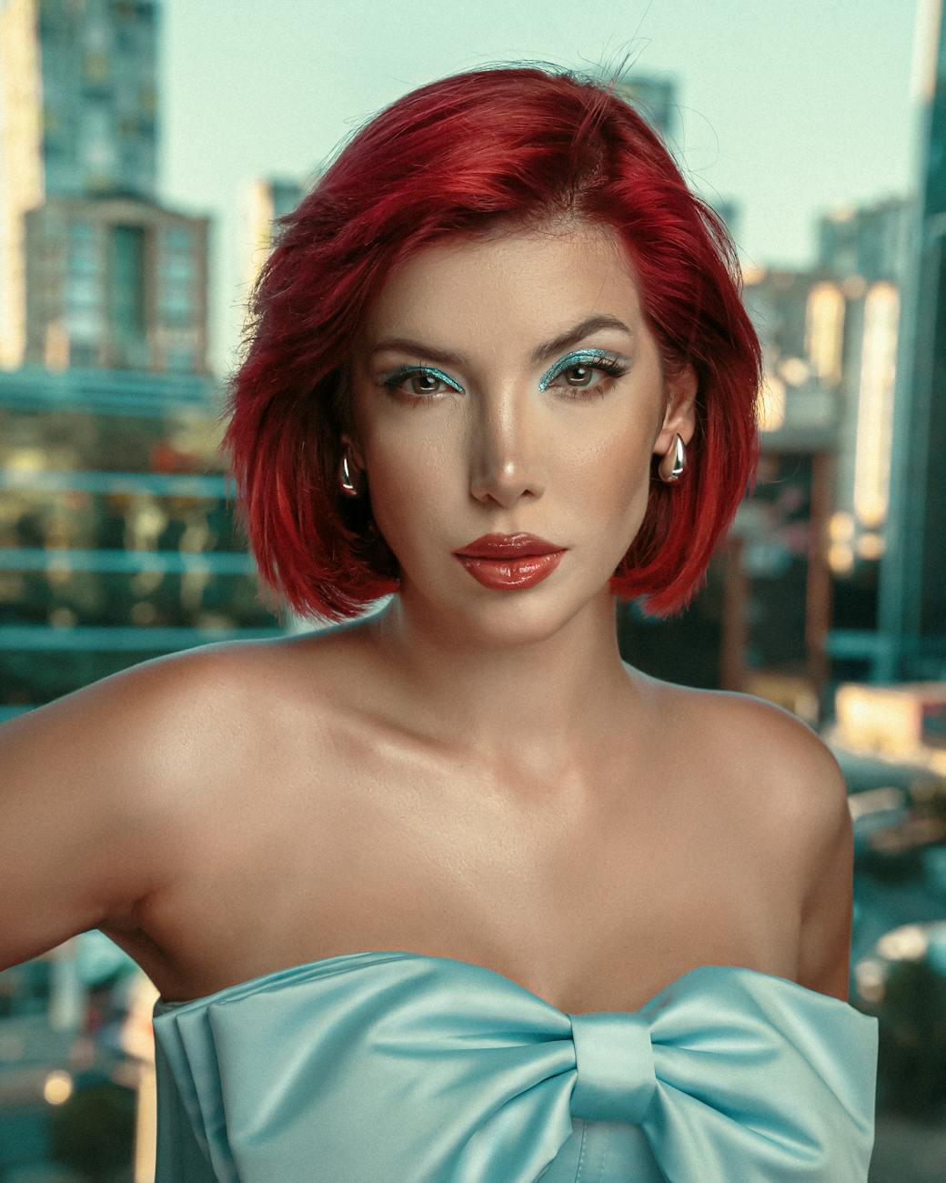 Portrait of a confident red-haired woman in a strapless dress with cityscape background [pexels]